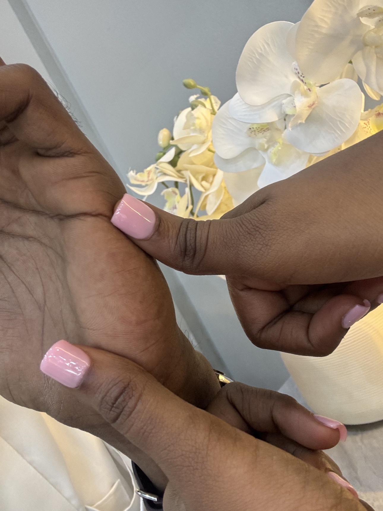 Our hands beside pale flowers