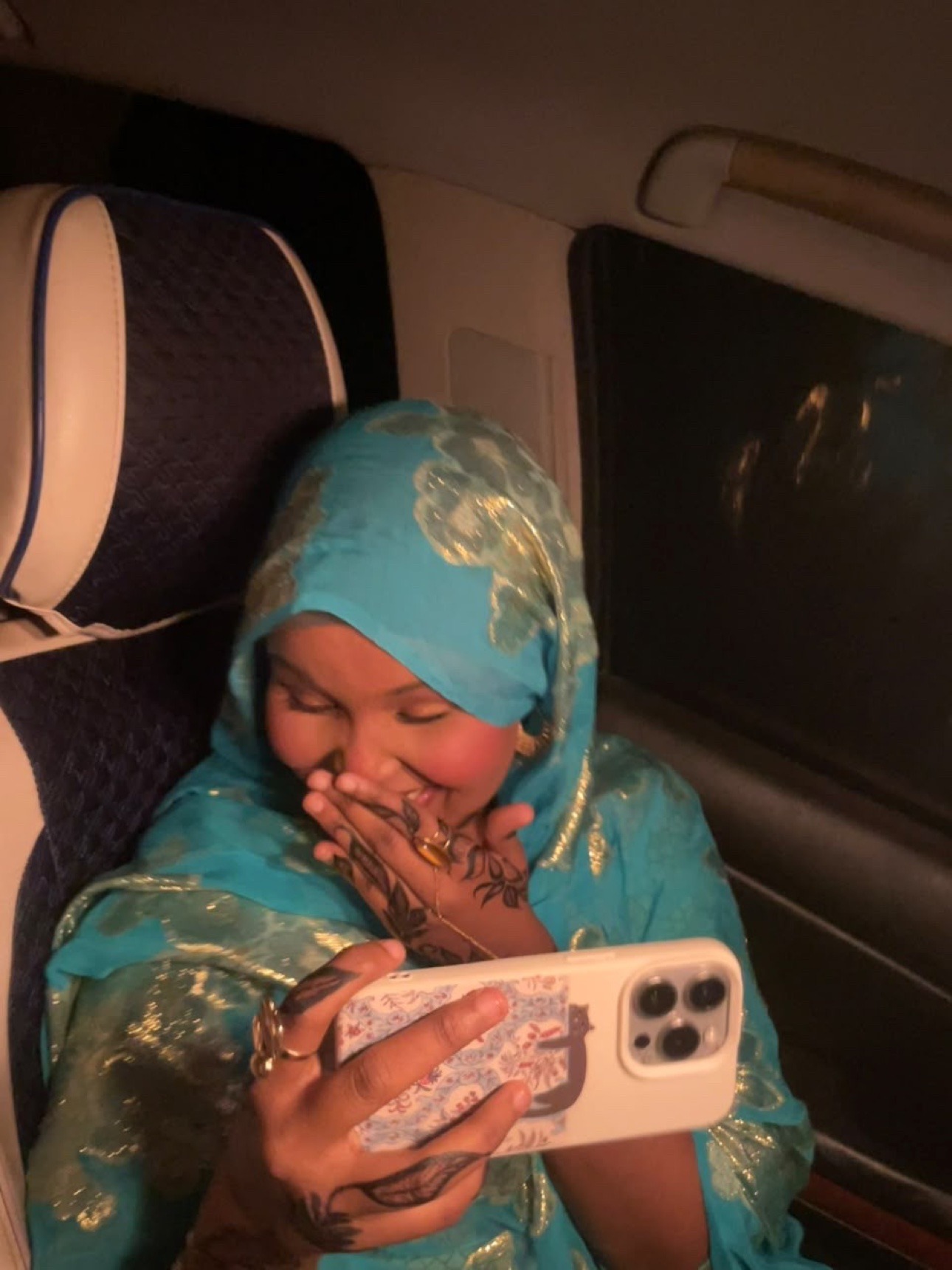 Her laughing in the car in a turquoise hijab
